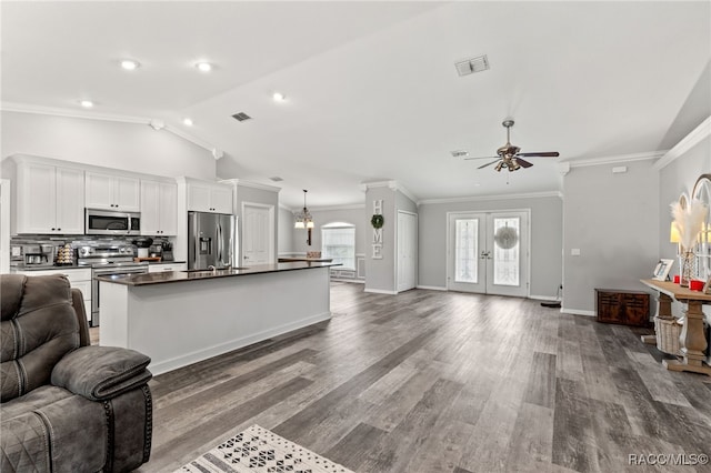 kitchen with stainless steel appliances, visible vents, open floor plan, dark countertops, and a center island with sink