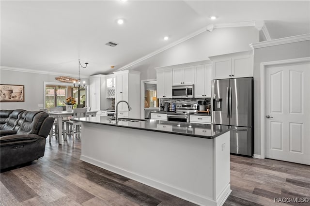 kitchen with dark countertops, visible vents, appliances with stainless steel finishes, open floor plan, and a sink