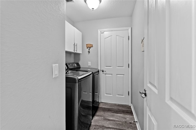 clothes washing area featuring dark wood-style floors, cabinet space, a textured wall, a textured ceiling, and washer and dryer