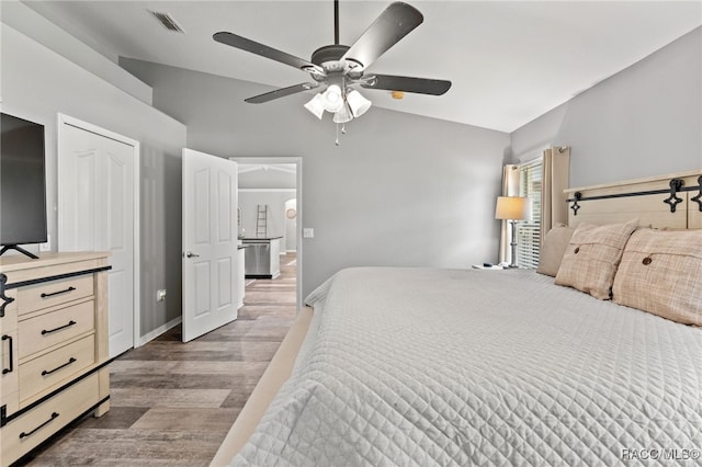 bedroom with light wood finished floors, visible vents, vaulted ceiling, ceiling fan, and baseboards