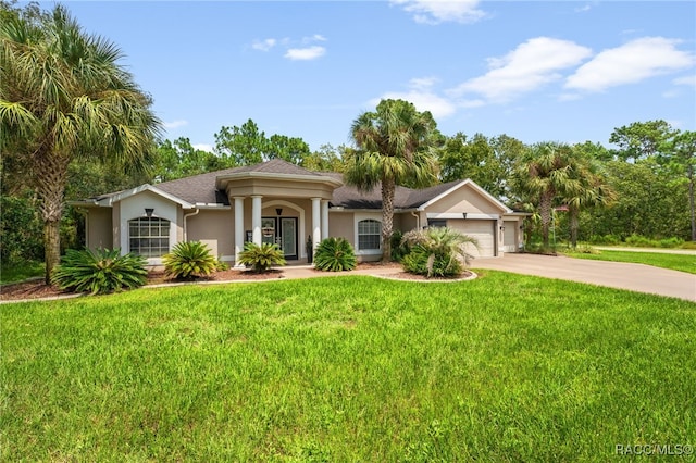 view of front of property with driveway, a front lawn, an attached garage, and stucco siding