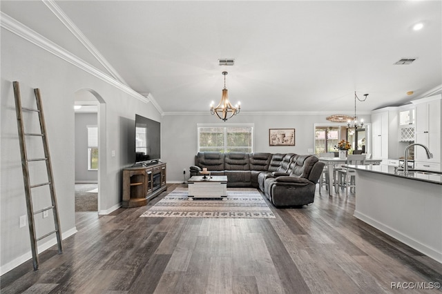 living area featuring a chandelier, arched walkways, crown molding, and dark wood-style floors