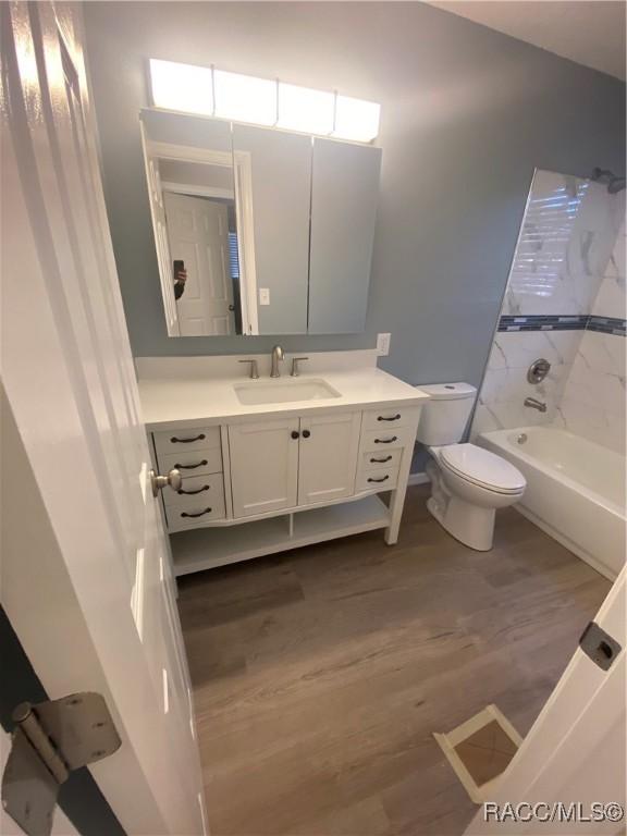 full bathroom with vanity, toilet, wood-type flooring, and tiled shower / bath