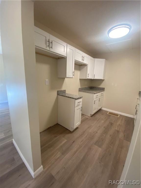 kitchen with wood-type flooring and white cabinetry