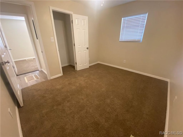 unfurnished bedroom featuring dark carpet and a closet