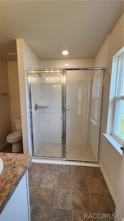 bathroom with vanity, toilet, and a shower with shower door