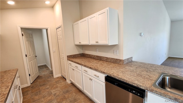 kitchen featuring stainless steel dishwasher, lofted ceiling, light stone counters, and white cabinetry