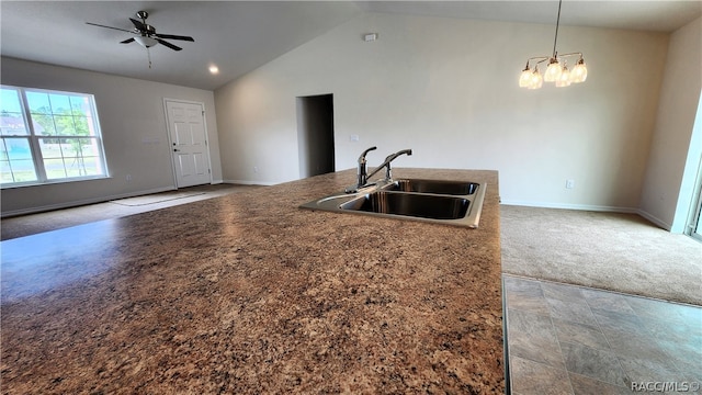 kitchen with light carpet, high vaulted ceiling, ceiling fan with notable chandelier, sink, and decorative light fixtures