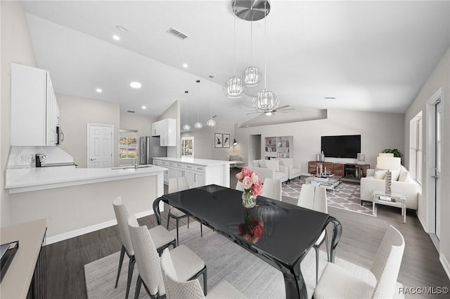 dining space with ceiling fan, sink, dark hardwood / wood-style floors, and vaulted ceiling