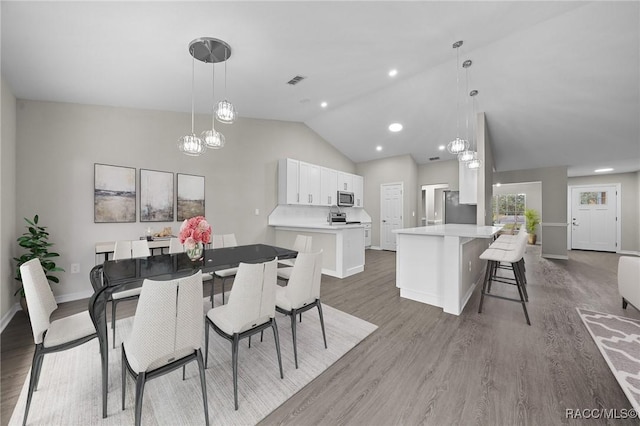 dining room with dark wood-type flooring, high vaulted ceiling, and a chandelier