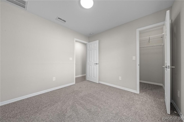 unfurnished bedroom featuring carpet flooring, a walk in closet, and a closet