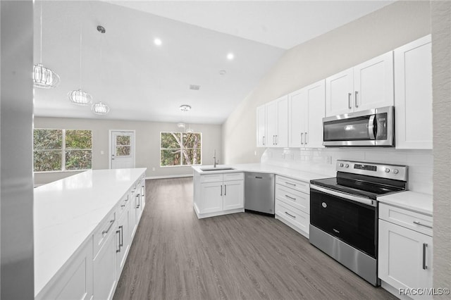 kitchen featuring pendant lighting, white cabinets, sink, vaulted ceiling, and stainless steel appliances