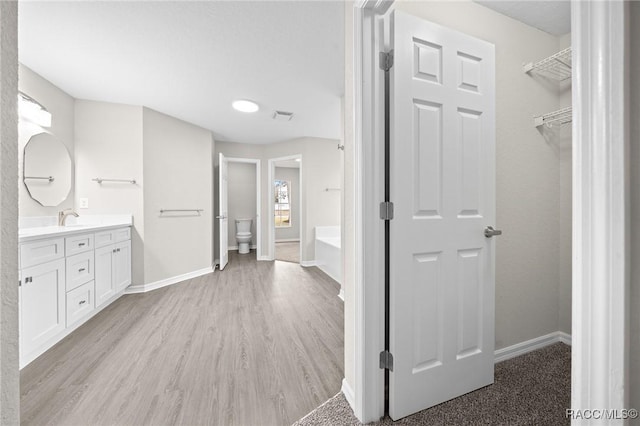 bathroom with a tub, hardwood / wood-style floors, vanity, and toilet