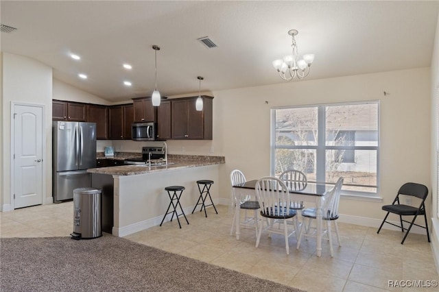 kitchen featuring appliances with stainless steel finishes, decorative light fixtures, light tile patterned floors, kitchen peninsula, and dark brown cabinets