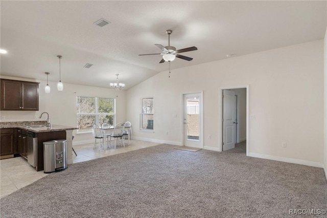 kitchen featuring sink, a kitchen bar, hanging light fixtures, light colored carpet, and light stone counters