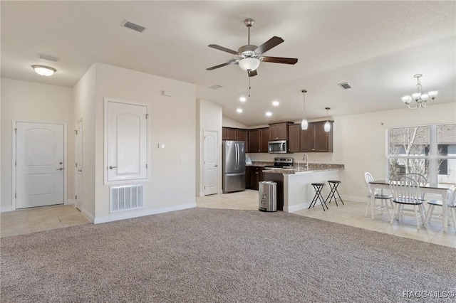 kitchen featuring light carpet, dark brown cabinets, a breakfast bar, and appliances with stainless steel finishes