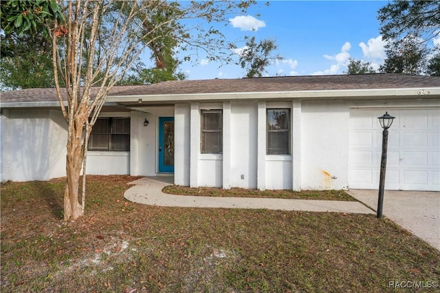 doorway to property with a garage and a yard