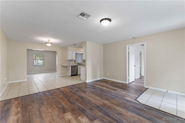 unfurnished living room with sink, a textured ceiling, and light wood-type flooring