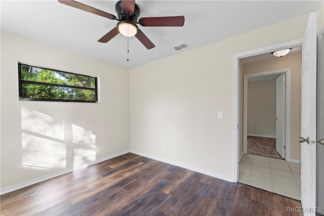 spare room featuring a textured ceiling, ceiling fan, and dark wood-type flooring