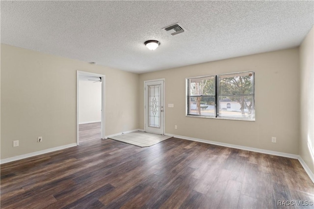 empty room with a textured ceiling and dark hardwood / wood-style floors