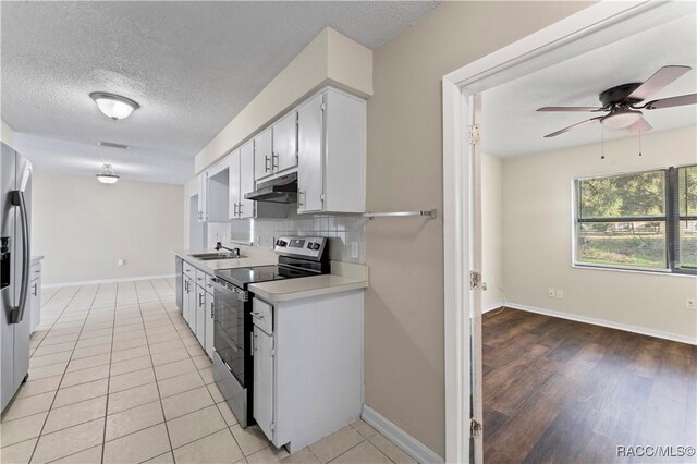 kitchen with light tile patterned flooring, appliances with stainless steel finishes, a textured ceiling, and sink