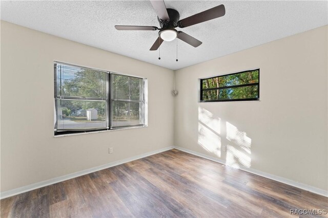 empty room with a wealth of natural light, ceiling fan, a textured ceiling, and hardwood / wood-style flooring