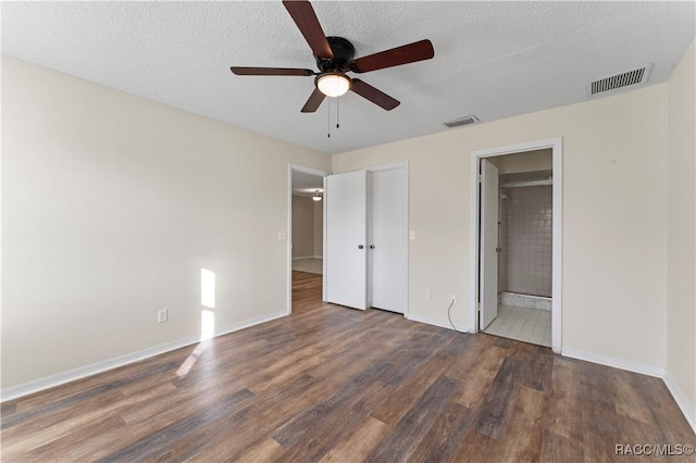 unfurnished bedroom featuring a textured ceiling, dark hardwood / wood-style flooring, ensuite bath, and ceiling fan