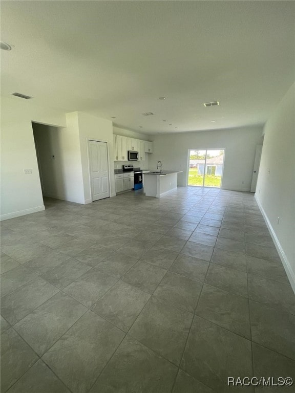 unfurnished living room featuring light tile patterned floors and sink