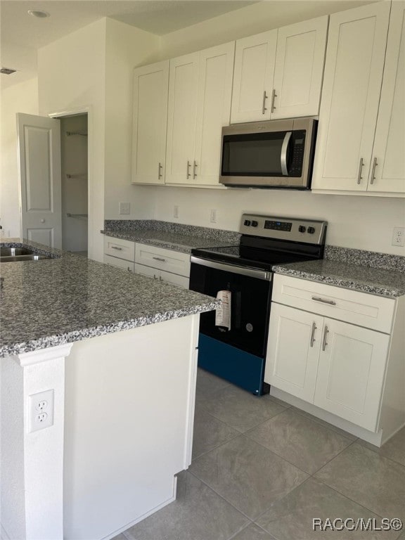 kitchen featuring sink, white cabinetry, stainless steel appliances, and dark stone counters