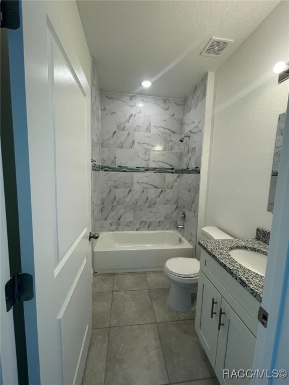 full bathroom featuring vanity, tile patterned flooring, tiled shower / bath combo, toilet, and a textured ceiling