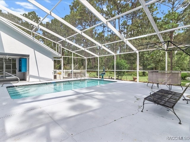 view of pool with glass enclosure and a patio area