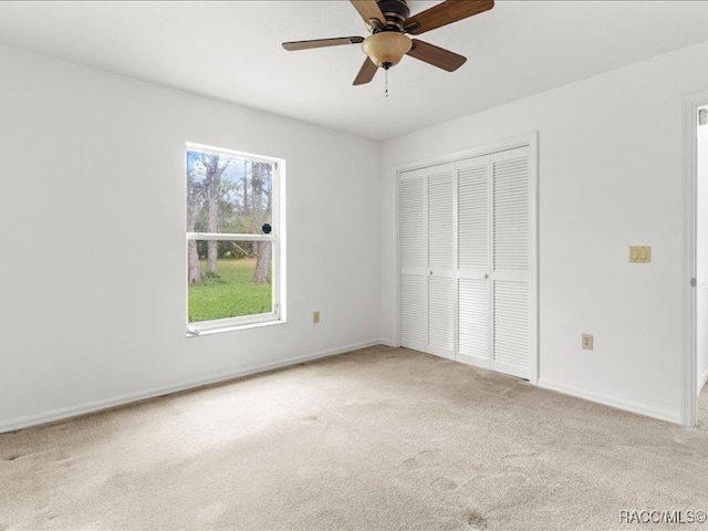 unfurnished bedroom with a closet, light colored carpet, and ceiling fan