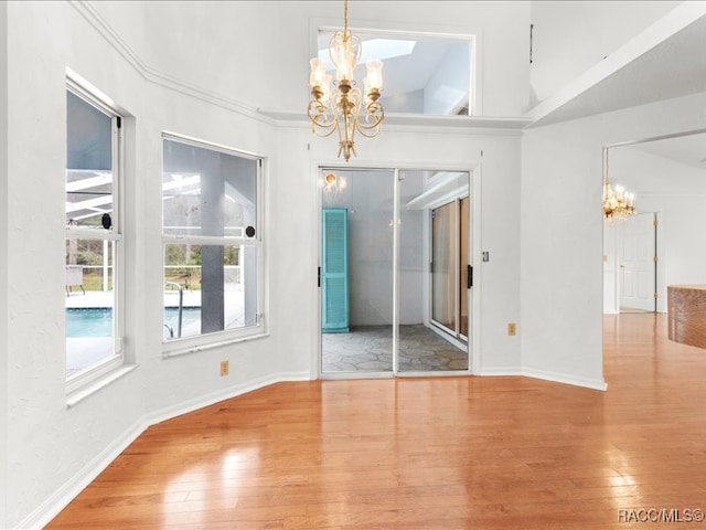 unfurnished dining area featuring hardwood / wood-style flooring, an inviting chandelier, and lofted ceiling