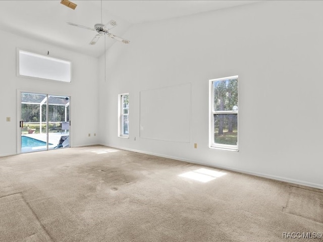 unfurnished living room featuring carpet flooring, high vaulted ceiling, a wealth of natural light, and ceiling fan