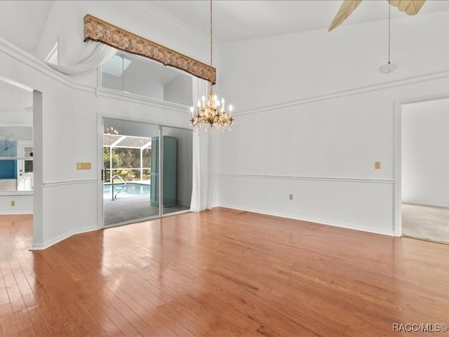 interior space with hardwood / wood-style flooring, ceiling fan with notable chandelier, and high vaulted ceiling