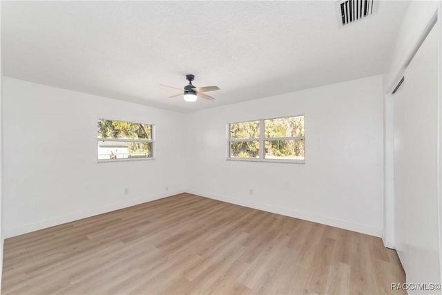 empty room with ceiling fan, a textured ceiling, and light wood-type flooring