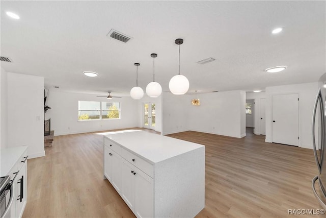 kitchen with pendant lighting, ceiling fan, light hardwood / wood-style floors, white cabinets, and a kitchen island