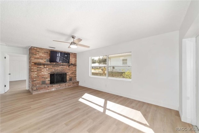 unfurnished living room with ceiling fan, a brick fireplace, a textured ceiling, and light hardwood / wood-style flooring