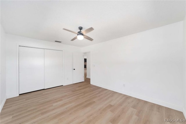 unfurnished bedroom featuring ceiling fan, light hardwood / wood-style floors, and a closet