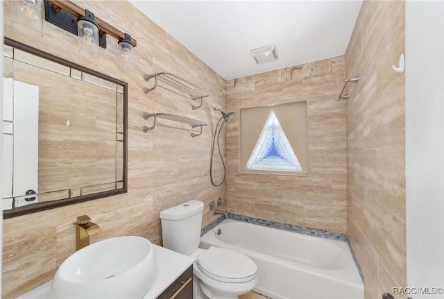 full bathroom with tiled shower / bath, tile walls, vanity, and toilet