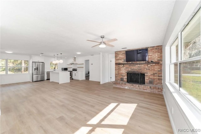 unfurnished living room featuring light hardwood / wood-style flooring, a fireplace, and ceiling fan