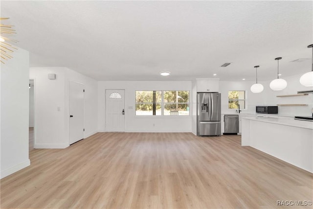 unfurnished living room featuring a textured ceiling and light wood-type flooring