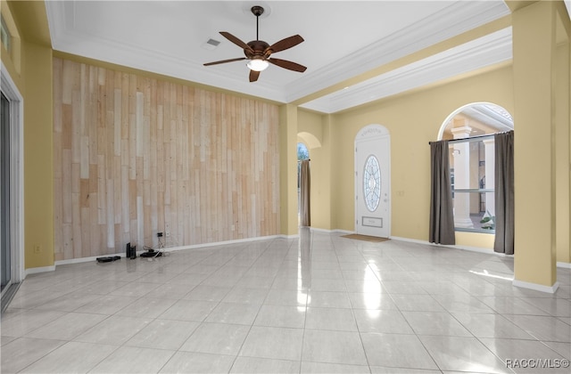 unfurnished room featuring ceiling fan, wood walls, light tile patterned floors, and crown molding