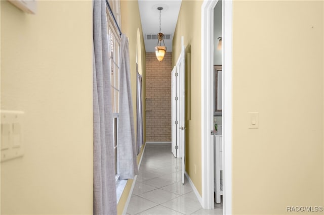 corridor featuring light tile patterned flooring and brick wall