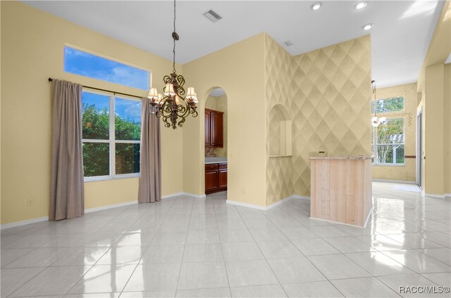 tiled empty room featuring tile walls and an inviting chandelier