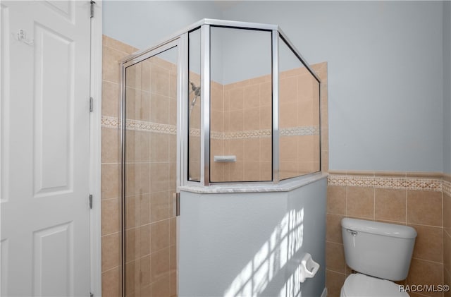 bathroom featuring toilet, tiled shower, and tile walls