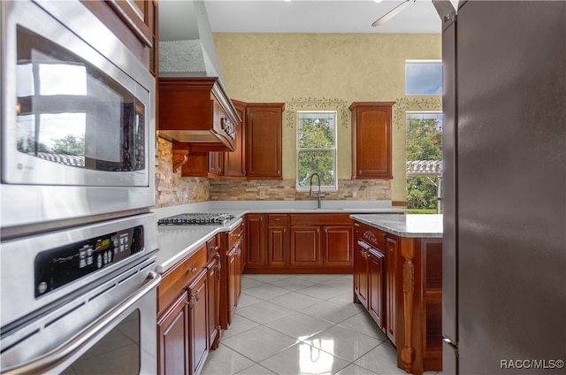 kitchen with decorative backsplash, light tile patterned floors, stainless steel appliances, and sink