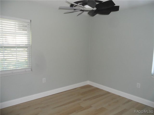 spare room featuring a ceiling fan, light wood-type flooring, and baseboards