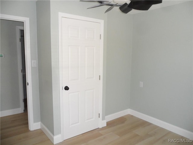 unfurnished bedroom featuring a ceiling fan, light wood-style flooring, and baseboards