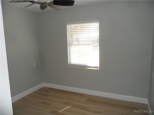 empty room with ceiling fan, wood finished floors, and baseboards